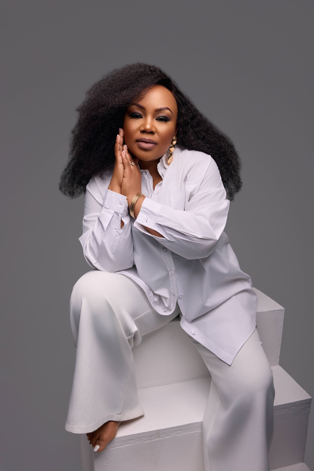 Lebo Thabethe seated in a white shirt and wide-leg trousers
